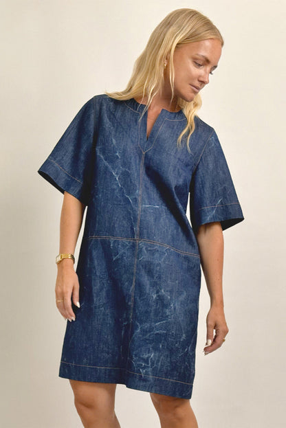Woman wearing a blue denim dress against a beige background